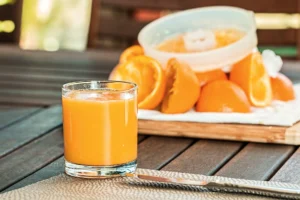 Kolorowe soki naturalne w szklankach, otoczone świeżymi owocami i warzywami.
